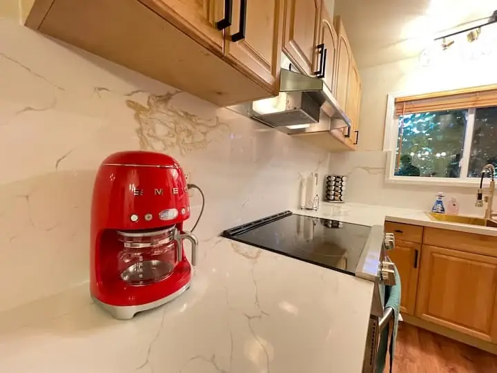 Red coffee maker and warm wood cabinetry in the Serene home's kitchen
