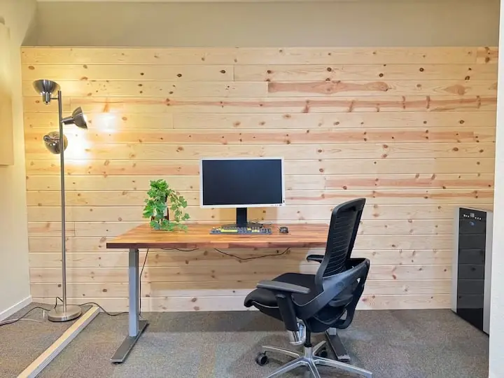 Wood-backed desk with monitor and ergonomic chair in the Sleek home